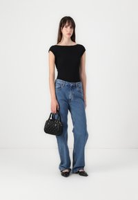 Black fitted top, high-waisted light blue jeans, black textured handbag, and black pointed-toe shoes with silver accents.