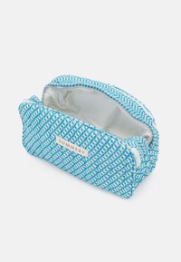 Bolso de cosméticos azul claro con un patrón de espiga texturizado, cierre de cremallera y interior blanco. Presenta una etiqueta de logo y forma rectangular compacta.