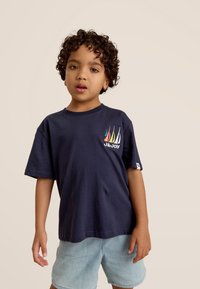 Marine katoen t-shirt met korte mouwen, voorzien van een kleurrijke zeilbootgrafiek en logo op de linkerkant van de borst. Gepaarde met lichtdenim shorts.