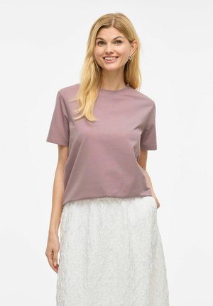 T-shirt léger mauve à manches courtes avec un col rond, fabriqué en tissu doux, associé à une jupe blanche texturée pour un contraste.