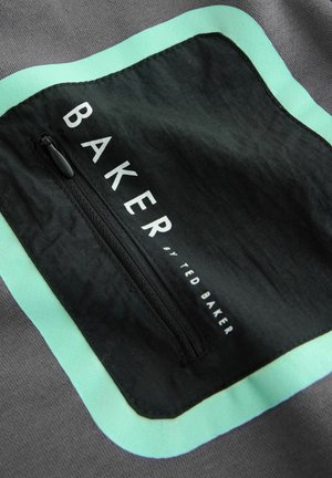 Fekete cipzáras zseb szürke szöveten, mentazöld díszítő szegéllyel. Fehérrel a "BAKER by TED BAKER" felirat olvasható. Simább textúra.