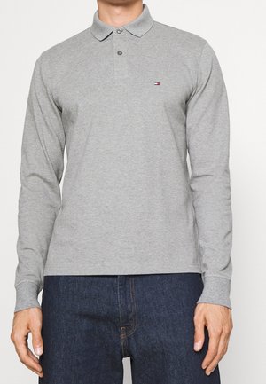 Graues Polohemd mit langen Ärmeln, einem Kragen, einer dreiknöpfigen Blende und einem kleinen Logo auf der Brust. Weicher Stoff mit glatter Textur.