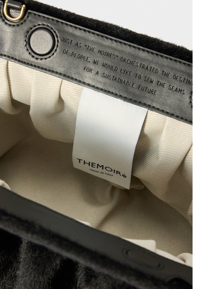 Borsa interna in lana nera con una finitura testurizzata, foderata in crema e con etichetta del brand. Sono visibili accenti in hardware dorato.