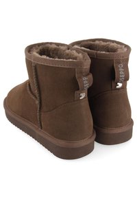 Stivali alla caviglia in suede marrone con una morbida fodera interna soffice. Presentano una suola in gomma piatta e un cordoncino sul retro con il logo del marchio.
