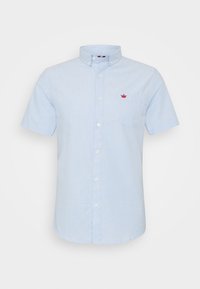 Camicia azzurra a maniche corte con colletto a bottoni, dotata di un piccolo logo rosso a forma di corona sul lato sinistro del petto e sulla tasca anteriore.