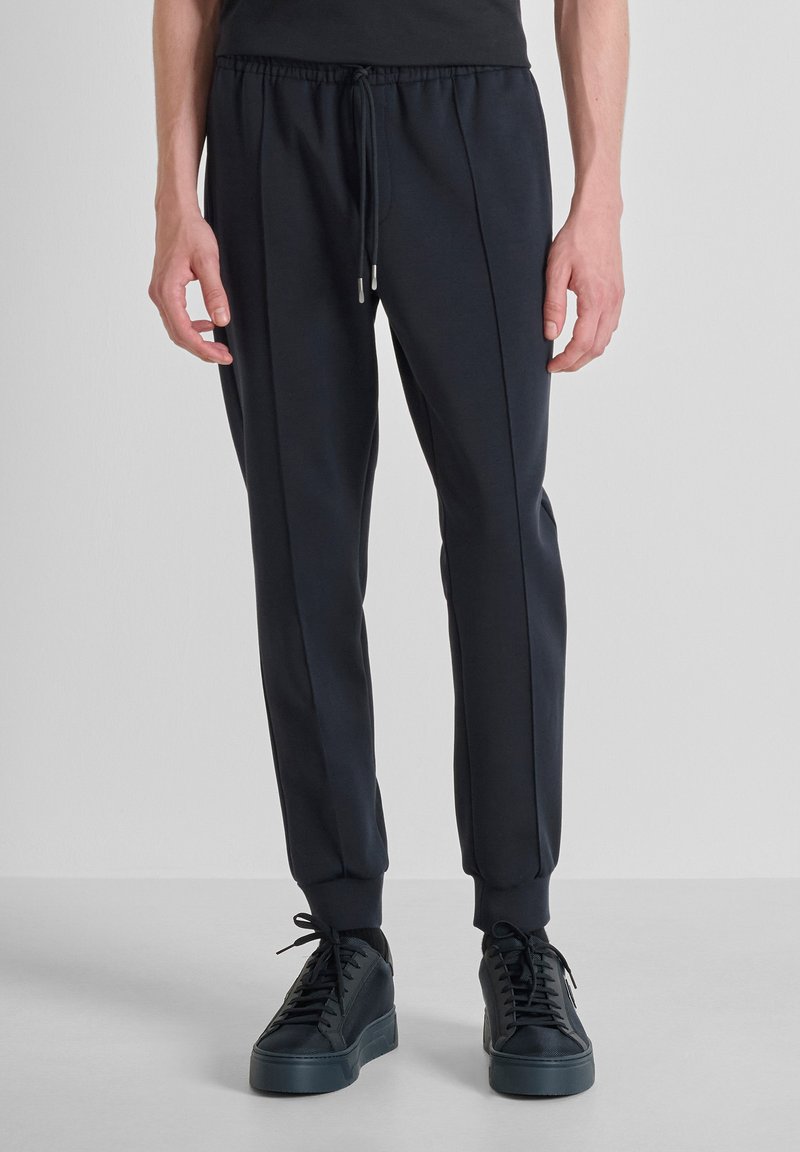 Marine joggerbroek van zachte stof, met een elastische tailleband en een trekkoord, en taps toe lopende boorden. Gepaard met zwarte sneakers.