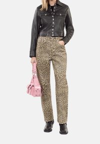 Chaqueta de cuero negra corta, pantalones de leopardo y botas negras de tobillo. Los accesorios incluyen un pequeño bolso rosa.