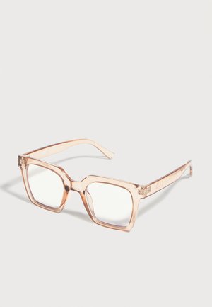 Transparante beige vierkante brillenmonturen met heldere glazen, rustend op een lichtgrijze ondergrond.