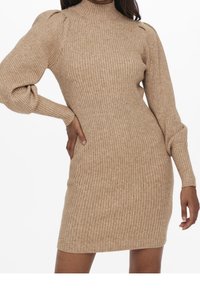 Robe en maille beige, présentant une texture côtelée, un col montant et des manches bouffantes qui se resserrent aux poignets, créant une silhouette ajustée.