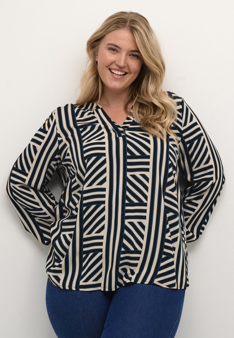 Langærmet bluse i beige og marineblå med markante stribede og geometriske mønstre. V-hals-design, afslappet pasform, blød stofstruktur.