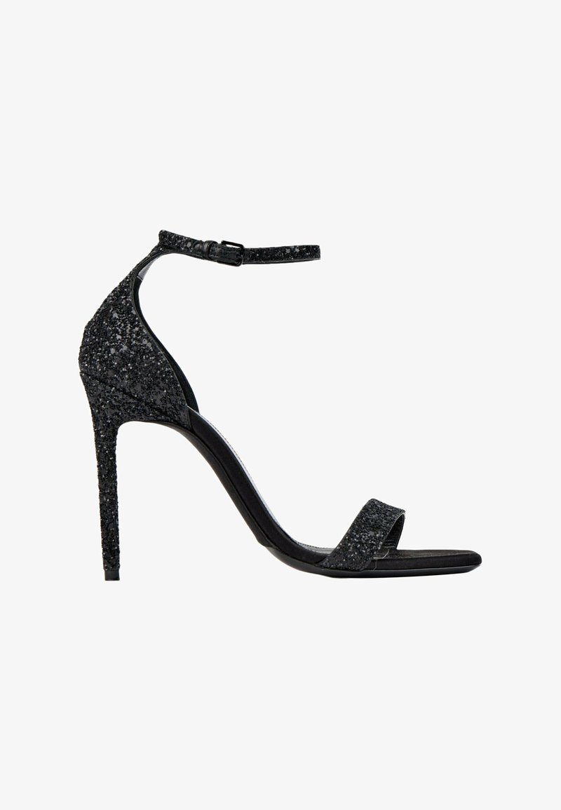 Sandale noire à talon haut avec bride à la cheville et bout ouvert, couverte de paillettes noires, vue de profil sur fond blanc.