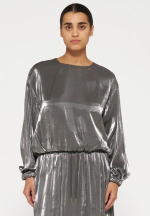 Metallic silbernes Kleid mit langen Ärmeln, elastischem Taillenbund und lässigem Schnitt. Glatte, glänzende Textur mit dezenten vertikalen Linien.