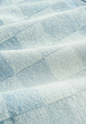 Ljust blå denimtyg med ett diamantmönster med distinkta rutor, som visar strukturerade vävningar och varierande nyanser av blått.