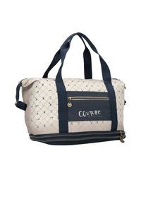 Quilted Tragetasche in Creme und Marineblau, mit geometrischem Muster. Enthält zwei robuste Griffe und eine frontseitige Reißverschlusstasche mit Logo.