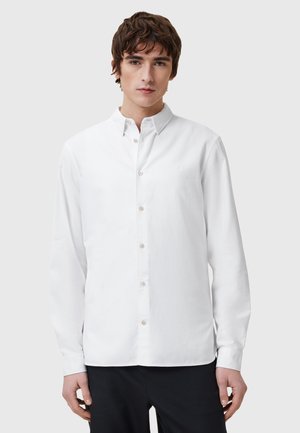 White long-sleeve button-down shirt in cotton fabric, featuring a classic collar, front placket with buttons, and subtle embroidery on the chest.