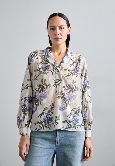 Cămașă cu butoni florală dintr-un material ușor, bej, cu un model de glicină albastră și verde; are un guler și mâneci strânse.