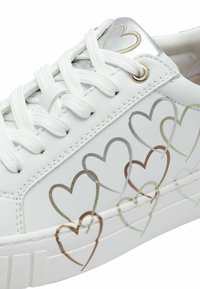 Sneakers bianchi con motivi a cuore in dettagli d'argento e oro, tomaia in pelle testurizzata, lacci piatti e suola in gomma.