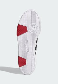 Biała gumowa podeszwa trampka z czarnymi pasami; posiada teksturowany czerwony akcent oraz okrągły wzór w pobliżu środka dla lepszej przyczepności.