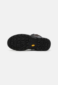 Schwarze Wanderschuhsohle mit tiefen Profilen, die durch gelbe Akzente und ein robustes Design für Grip auf verschiedenen Untergründen gekennzeichnet ist. Aus strapazierfähigem Gummi hergestellt.