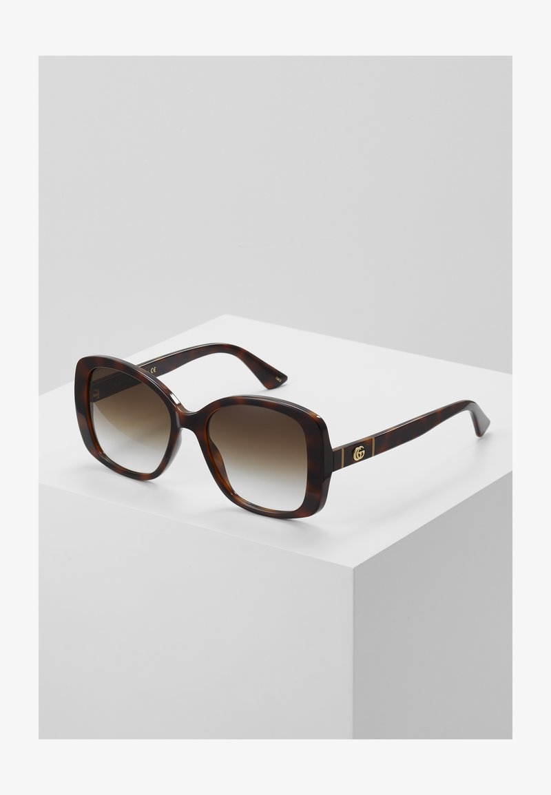 Ochelari de soare pătrați cu model tartă, dotati cu lentile degrade. Accente din hardware auriu pe braț, cu un detaliu distinct al logo-ului. Textură netedă.