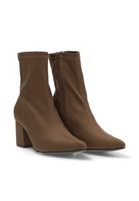 Botas de tobillo marrones con un tejido liso y elástico, puntera afilada y tacón cuadrado grueso; cuentan con un cierre lateral de cremallera y detalles de costura en contraste.