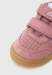 Różowe zamszowe buty z podwójnymi paskami na rzep, siateczkowymi wstawkami, perforowanym noskiem i gumową podeszwą; zdobione przeszyciami.