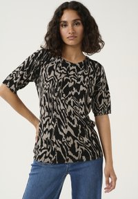 Sort og beige kortærmet top med et abstrakt dyreprint, rund halsudskæring og blød strikket tekstur. Kombinationen er med blå jeans.