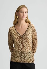 Maglione beige con motivo leopardato marrone, scollo a V, maniche lunghe e orlo aderente. Tessuto morbido con un materiale leggero e traspirante.