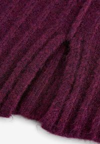 Gros plan sur un tissu tricoté côtelé de couleur violette foncée avec des fibres de laine texturées et duveteuses et des motifs de tricotage verticaux.
