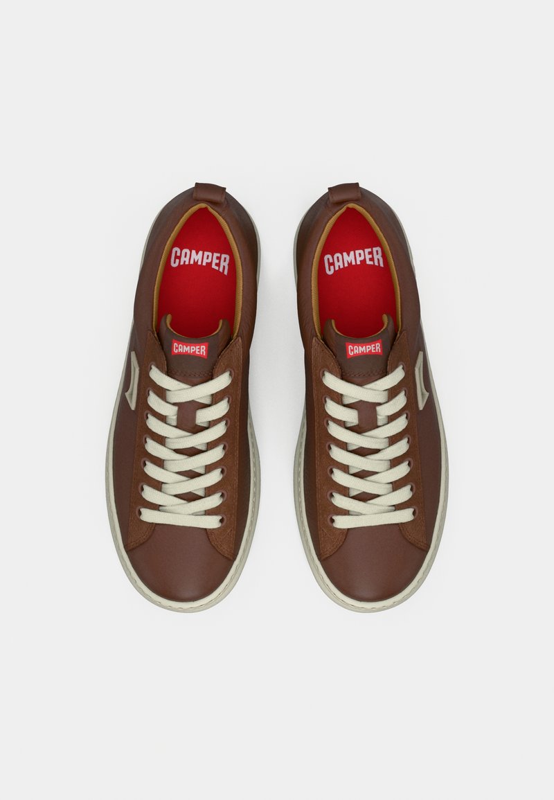 Brown leather sneakers with cream laces and insoles. Features a white rubber sole and a prominent logo displayed on the tongue.