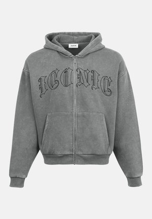 Grå zip-up hoodie med framfickor, med texten "ICONIC" i svart, tillverkad av mjukt tyg med en avslappnad passform och ribbade muddar.
