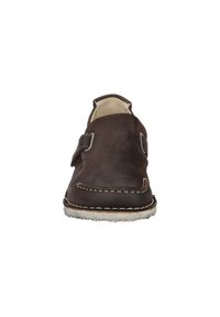 Brown leather shoe with a soft texture, featuring a strap closure, contrasting stitching, and a rounded toe design.
