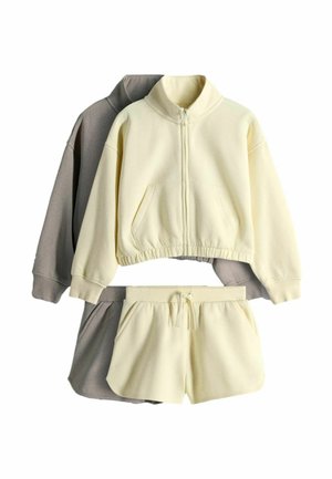 Dwa komplety odzieży z polaru z szortami na sznurku i kurtkami na zamek, jeden w kolorze kremowym, drugi w kolorze taupe.