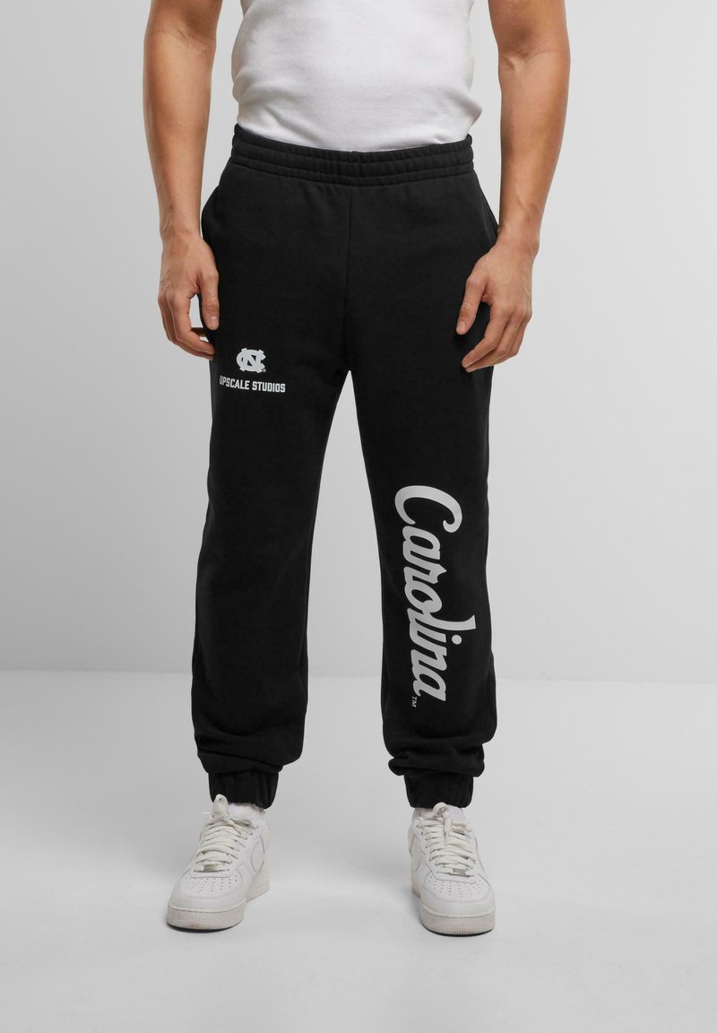 Sorte sweatpants med elastisk talje, ribbede manchetter og hvid trykt tekst "Carolina" og "UPscale Studios." Fremstillet i bomuldsmateriale, afslappet pasform.