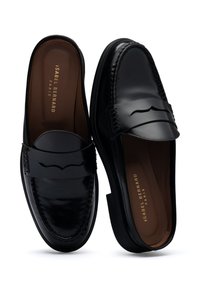 Black leather loafers with a shiny finish, featuring a decorative strap and stitched detailing along the edges. Smooth interior lining.