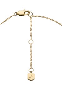 Collana in oro con chiusura a gabbiano, caratterizzata da un piccolo ciondolo a forma di scudo inciso con la lettera "F" appeso a una corta catena verticale.
