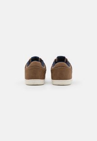 Bruine suède sneakers met een marineblauwe stofvoering, afgeronde vorm, witte rubberen zool en contrasterende accenten op de hiel en zijkanten.