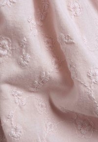 Light pink fabric with textured floral embroidery. The design features clusters of flowers connected by delicate stitching, creating a soft appearance.