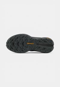 Semelle de chaussure en caoutchouc noir avec un motif de crampons profonds et le logo Continental orange au centre et près du talon.