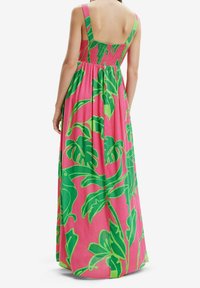 Robe maxi avec un fond rose vif et de grands motifs de feuilles vertes, dos smocké et larges bretelles.