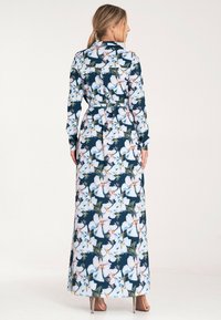 Długa kwiecista sukienka na ciemnonavy tle, z białymi i różowymi kwiatami, długimi rękawami i paskiem wiązanym w talii. Satynowa faktura.