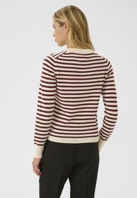 Pull rayé aux couleurs bordeaux et crème, avec des manches longues et des poignets côtelés, présenté de dos sur un fond uni.