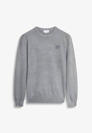 Suéter gris hecho de un suave tejido de punto, con un cuello redondo y puños acanalados. Incluye un pequeño parche de logo texturizado en la parte delantera.