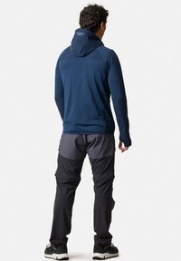 Hooded, donkerblauwe lange mouwen jas met grijze accenten, gecombineerd met grijze en zwarte broek. De stoffen lijken lichtgewicht en flexibel.