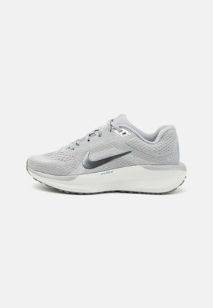 Zapatilla deportiva gris con parte superior de malla transpirable, logo Swoosh gris oscuro, talón acolchado y entresuela blanca con acentos en azul claro.