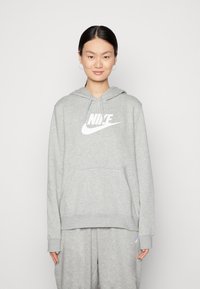 Grijze hoodie met een voorzak, met een groot wit Nike-logo op de borst. De materialen lijken zacht en gestructureerd, met een capuchon met trekkoord.