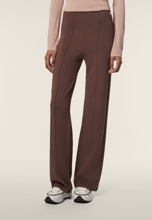 Pantaloni marroni a gamba larga con una texture liscia, cuciture in rilievo e vita alta, abbinati a sneakers bianche con dettagli neri.