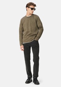 Olivgrüner Strickpullover mit Rundhalsausschnitt; schwarze Slim-Fit-Jeans; schwarze Schuhe; Sonnenbrille; glatte Textur; lässiger Schnitt; minimale Details.