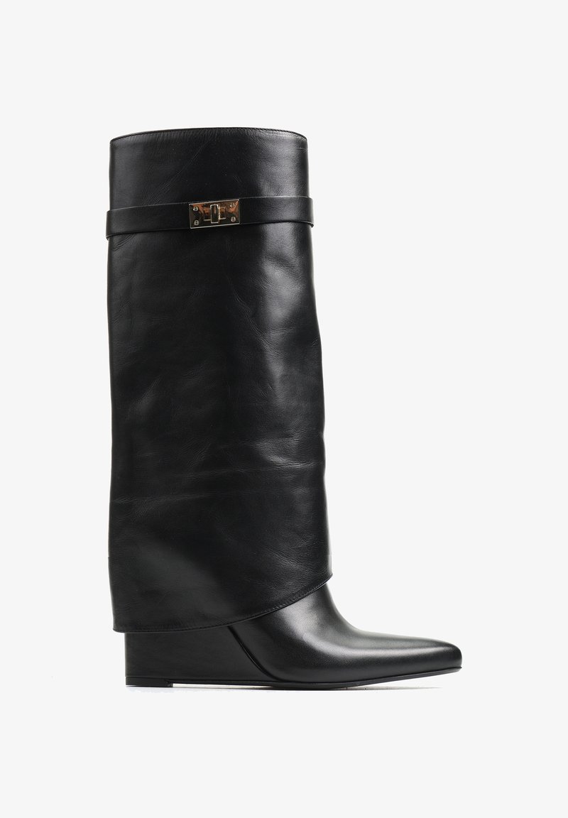 Czarne skórzane botki na koturnie z luźniejszą cholewą, z płaskim paskiem i metalowym akcentem. Spiczasty nosek z gładką powierzchnią.