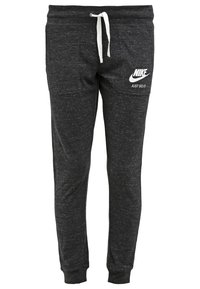 Černé, texturované tepláky s bílou šňůrkou a logem "Nike". Na levé stehně je bíle tisknutý slogan "Just Do It".